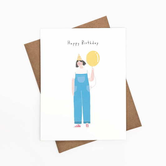 A Happy Birthday card with a female wearing overalls, yellow party hat, and yellow balloon.