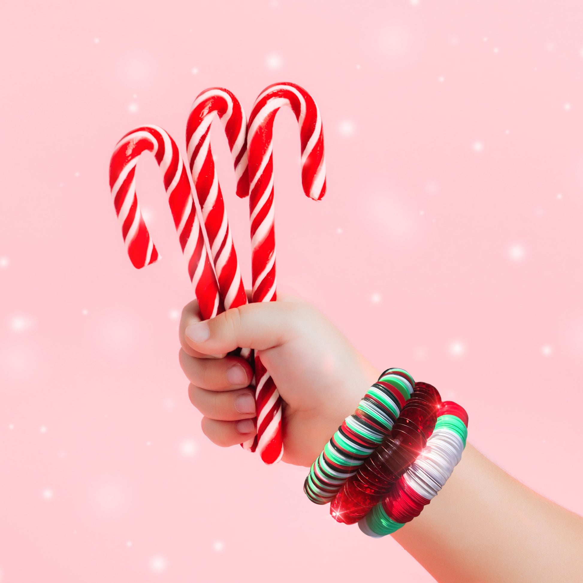 Holiday image showing 3 candy canes and 3 D.I.Y. Bracelet Kit Holiday Edition worn on the wrist.