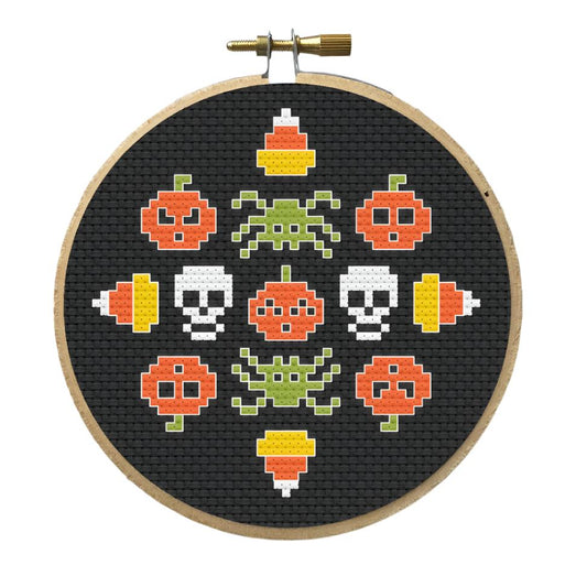 Creepy Halloween Cross-Stitched Kit available now on KangyCo.com with glow-in-the-dark thread. It has a black background candy corn (top, left, bottom, right), 5 pumpkins, 2 skulls, and two spiders.