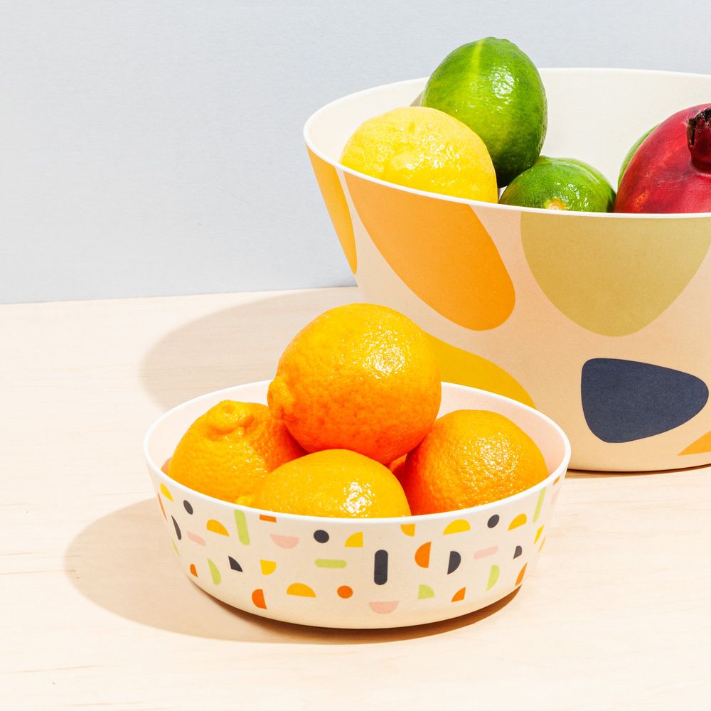 Terrazzo Bamboo Bowl shown holding 5 oranges, displayed in front of a bigger bamboo bowl (not for sale).