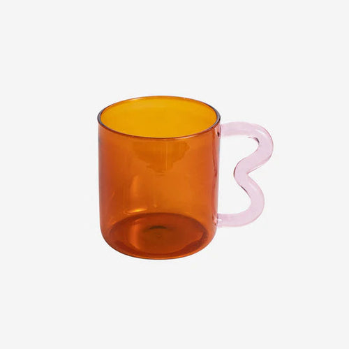 The B style of the Retro Wavy Mug in an amber translucent glass mug with an ergonomic wavy handle in pink.