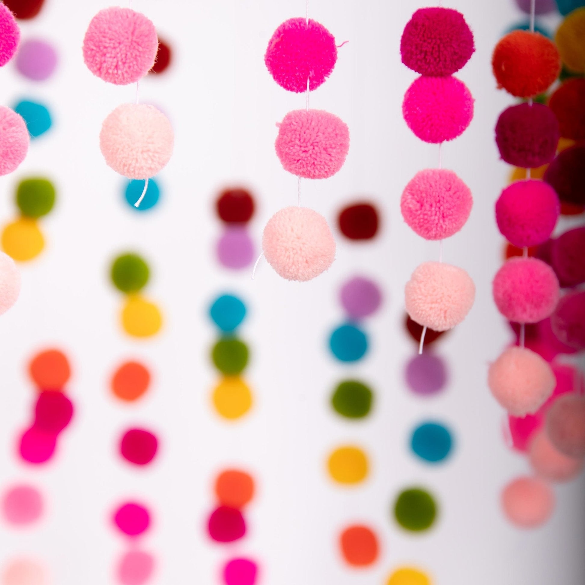 Shows the colorful Bead Stair Pom-Pom Mobile Craft from the "Discover Like Maria" Kids Crafts Box.