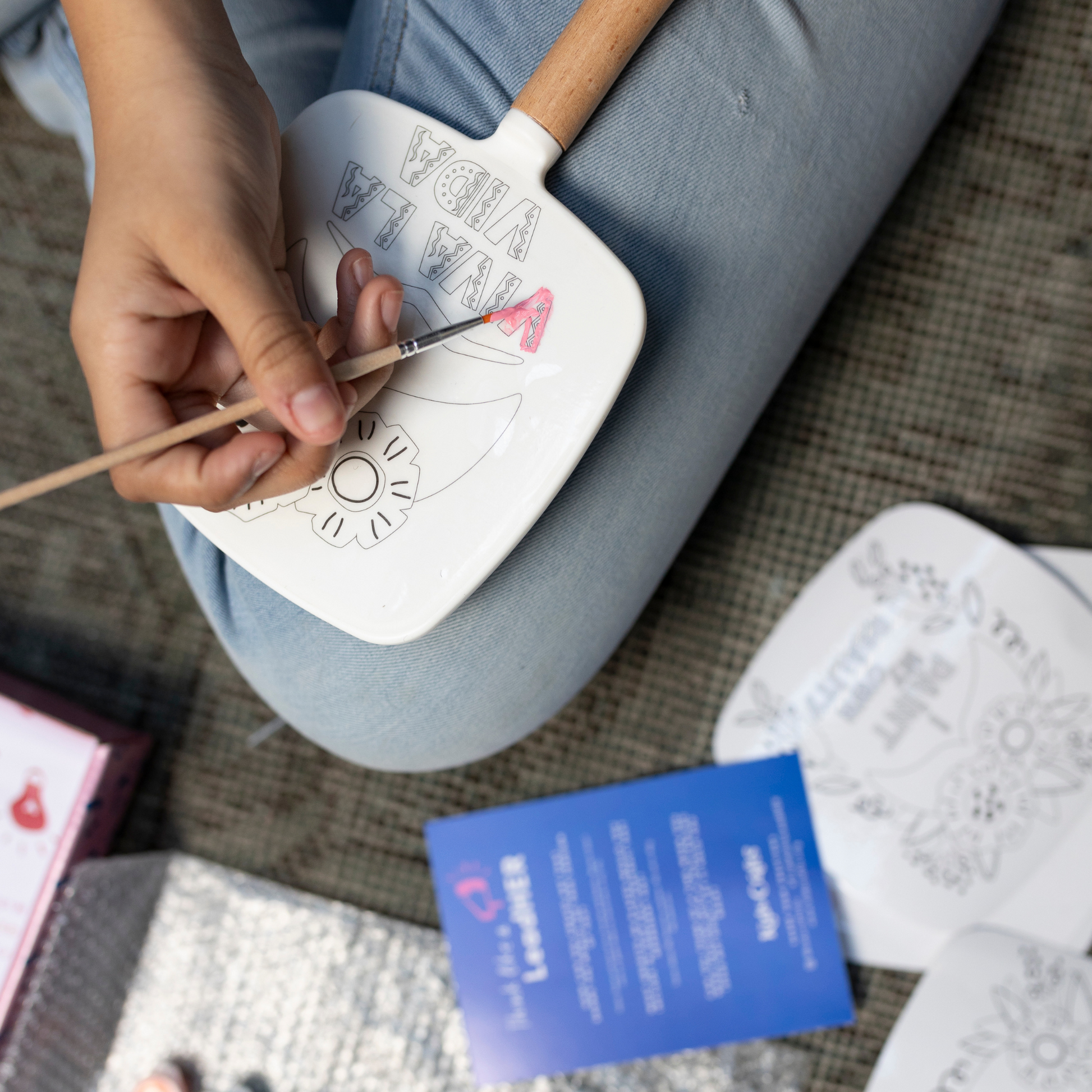 Image of child painting the back of a hand-held mirror from the Create Like collection "Frida Kahlo" Self-Portrait Mirror Painting Kit.