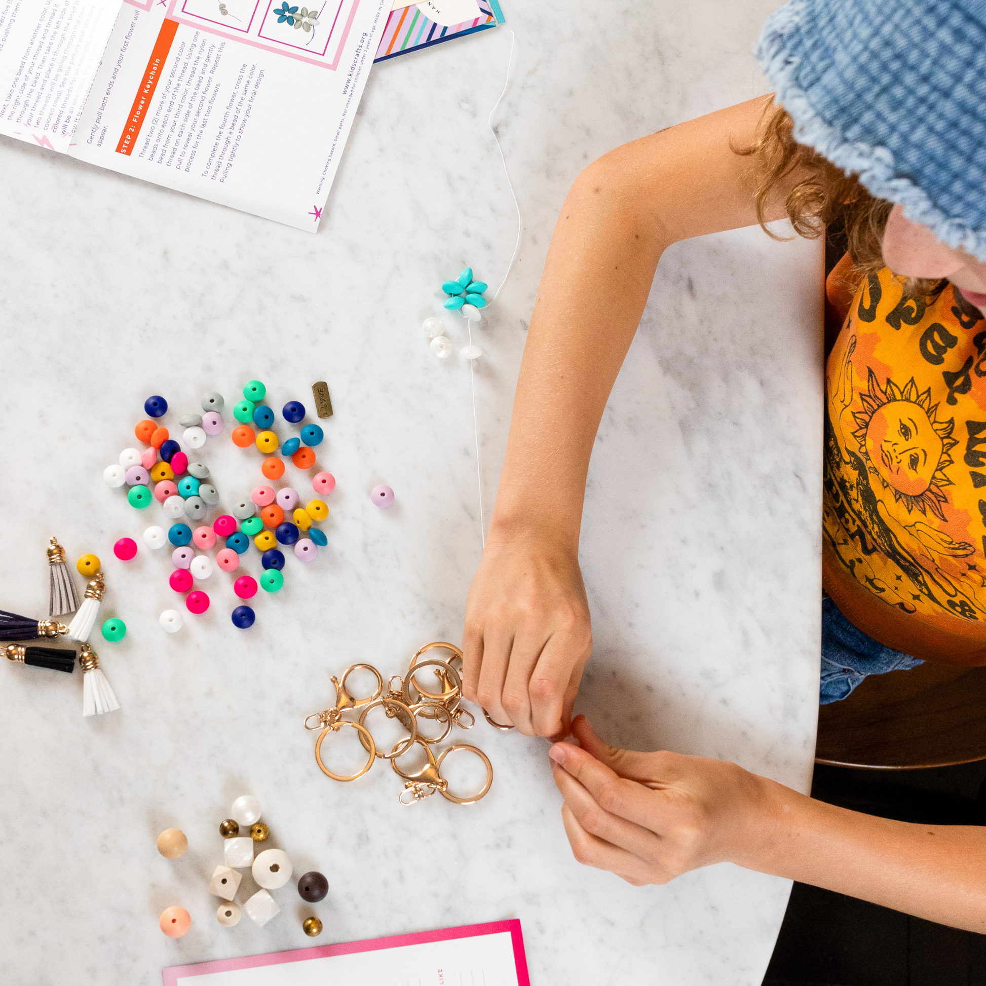 Shows a young girl making the keychains using the supplies from the Kids Craft Keychain Kit available at Kangyco.com.