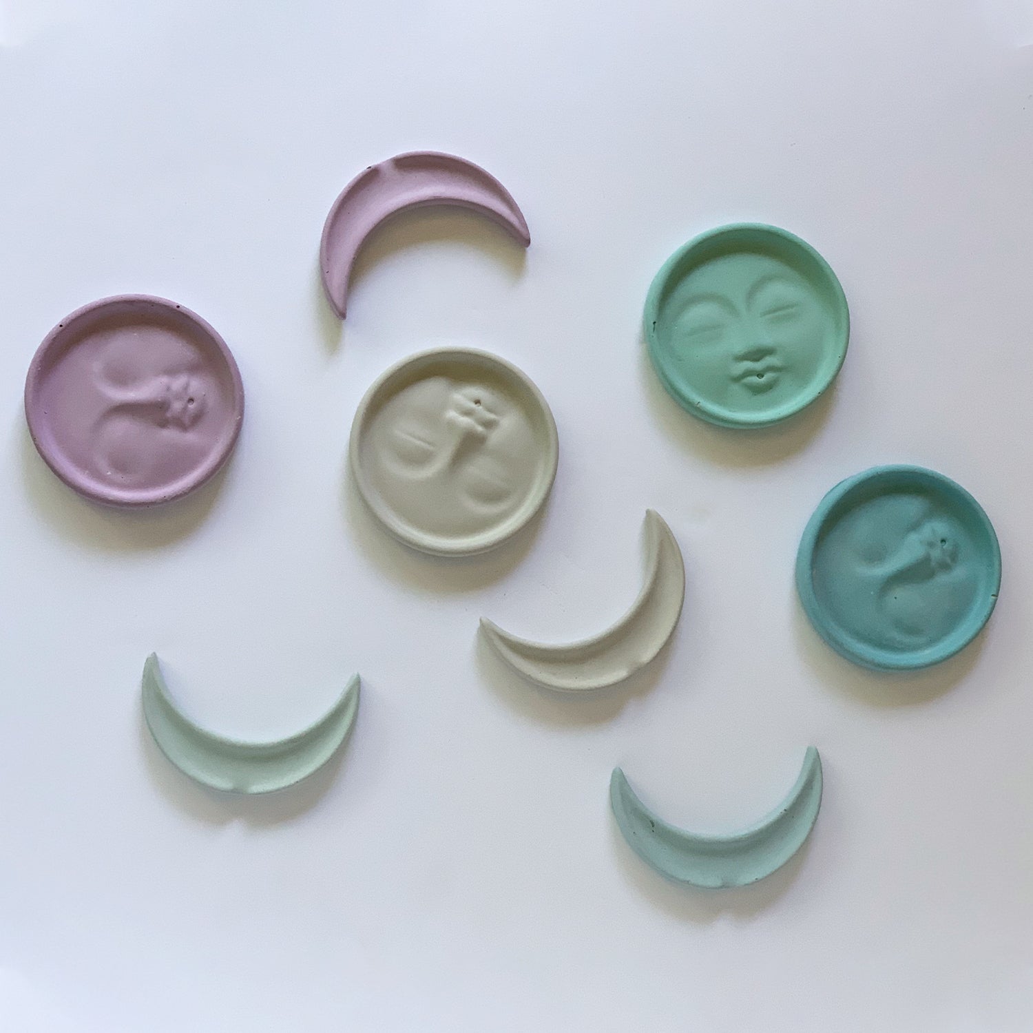 Another Point of View of the concrete moon designs shown in purple, gray, green, and blue.