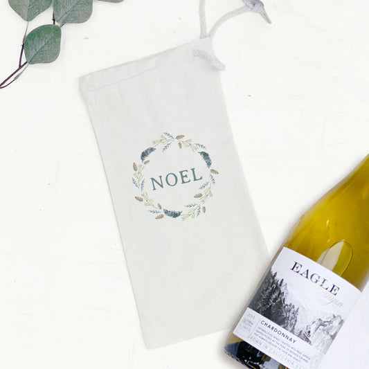 A canvas wine bag with a pine wreath decoration and the text "NOEL" in the middle.