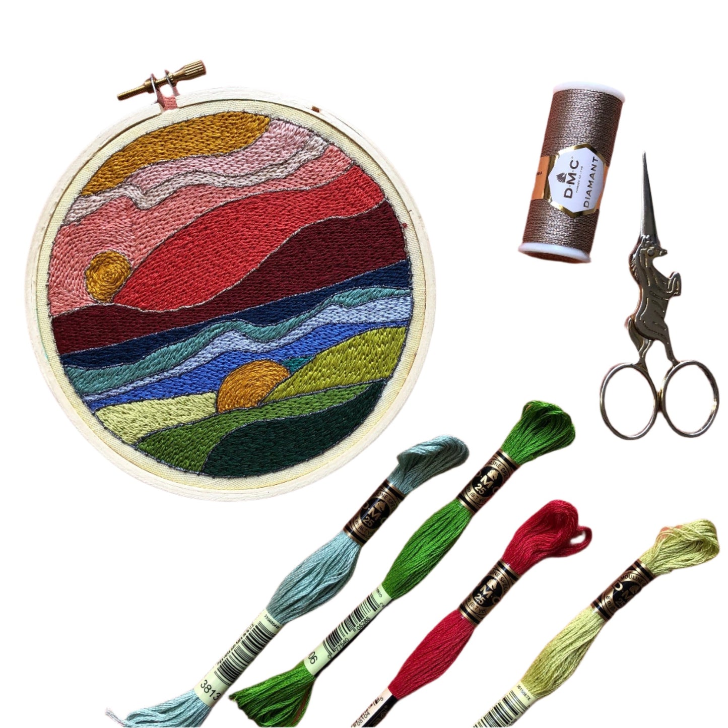 Colorful and vibrant stained glass landscape embroidery kit with the finished design, threads, and scissors.