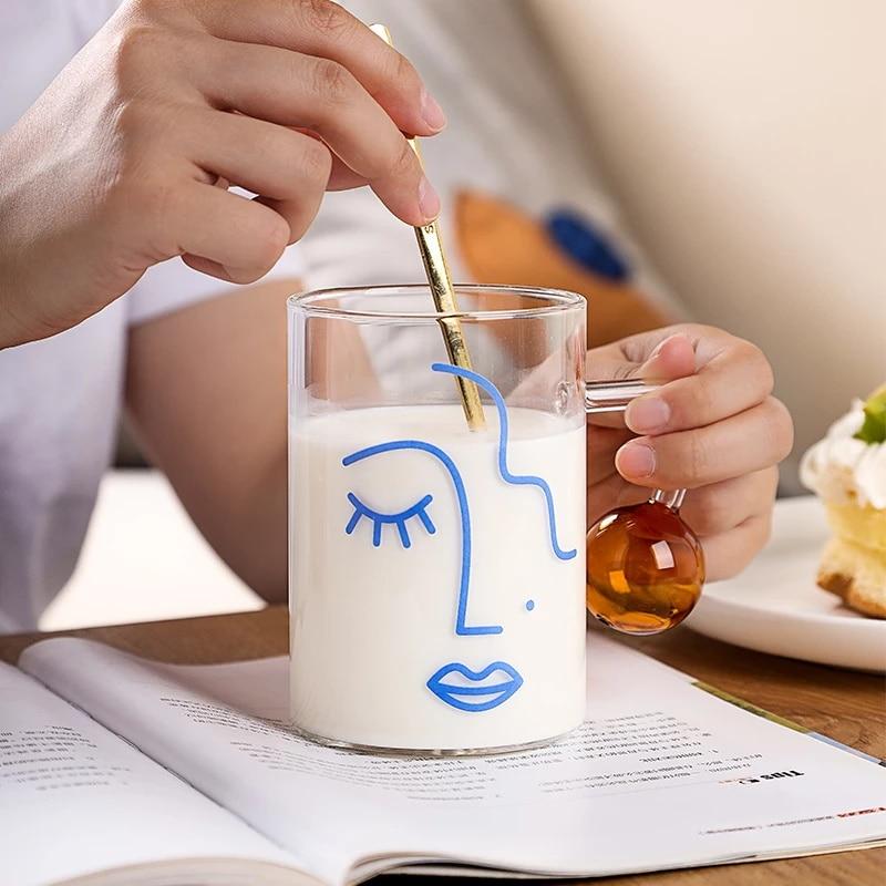 Tall Abstract Mug used for milk and person is moving the milk with a spoon (not available).