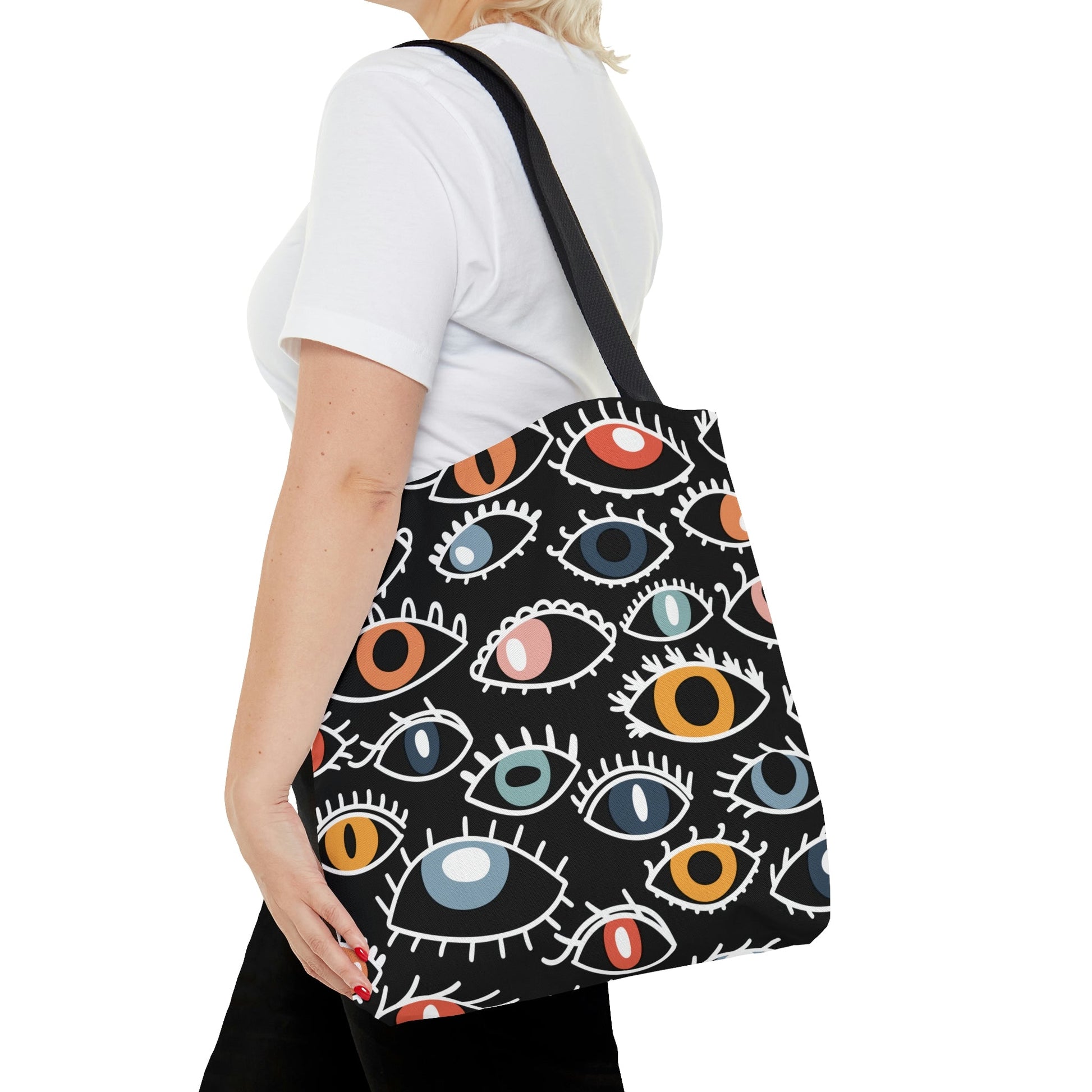 All over eyes tote bag worn by a woman.